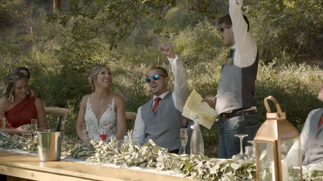 A groomsman gives a toast as Danielle and Scott laugh at the head table.