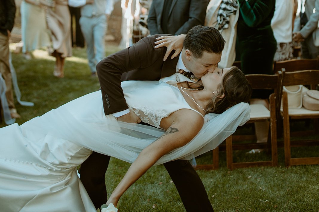 Devin dips Emily for a kiss in the aisle in front of the white house as their guests cheer