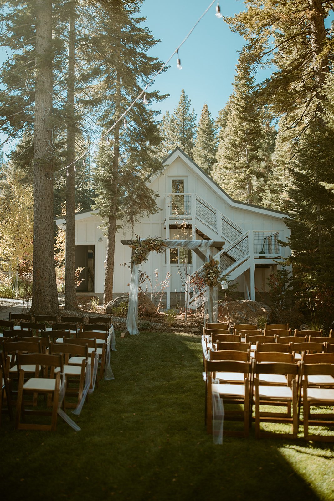 Wooden chairs and the aisle on the private estate, the white house and pines behind