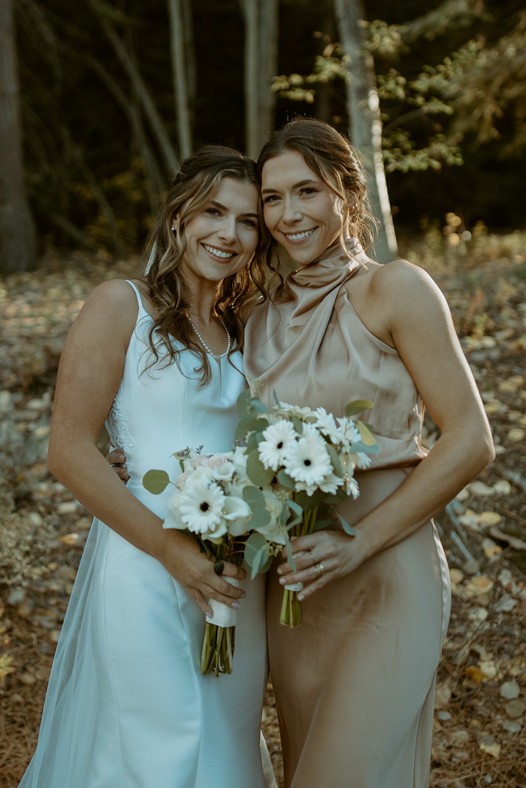 Emily and a bridesmaid lean cheek to cheek, smiling