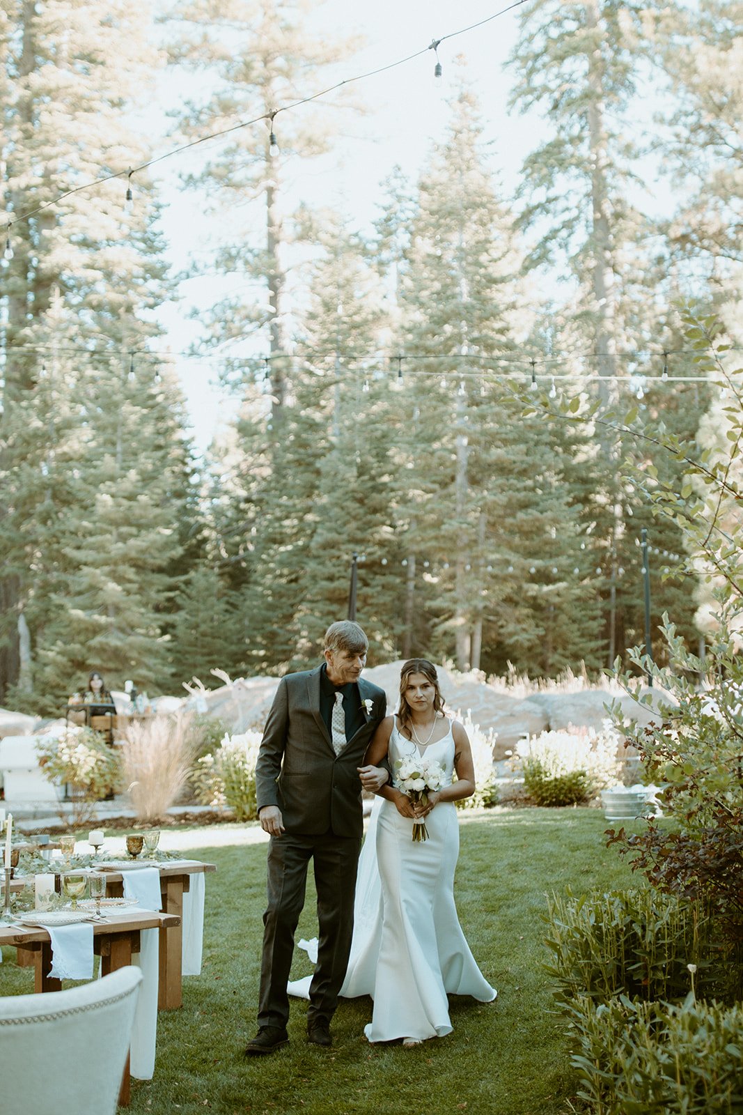 Emily walks across the lawn on the arm of a loved one