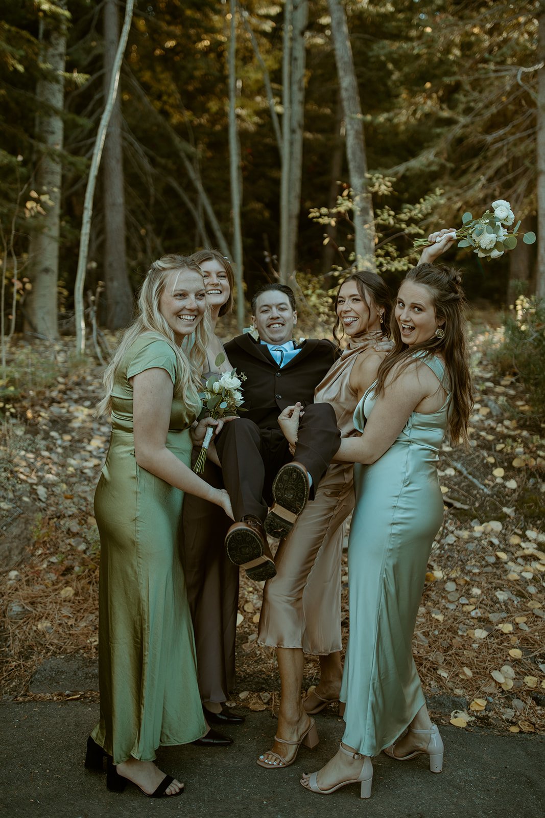 The bridesmaids lift Devin off the ground, laughing