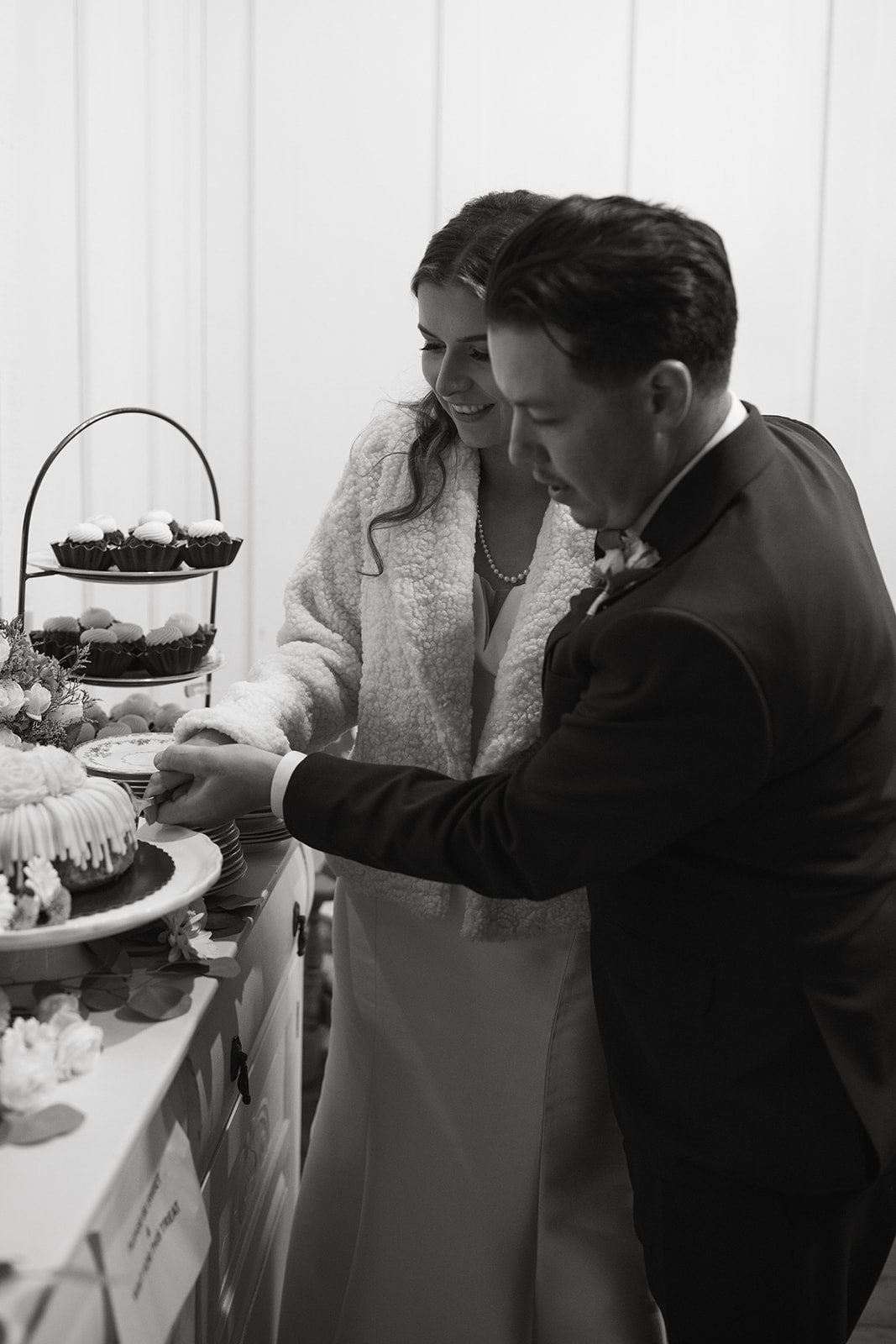 Emily and Devin cut the cake, in black and white