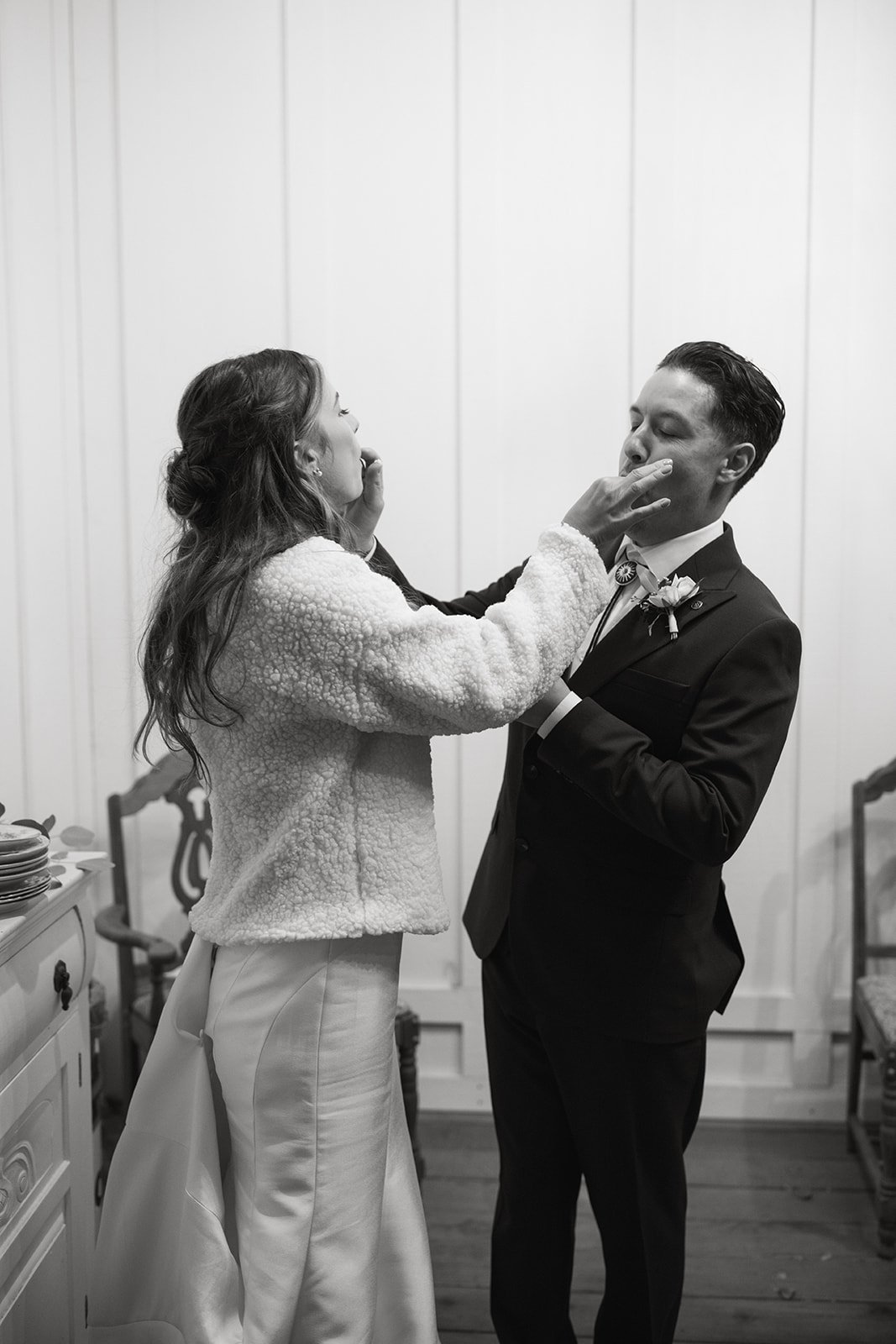 Emily and Devin feed each other cake, in black and white