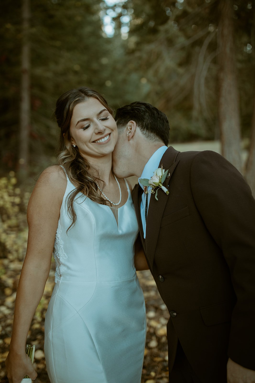 Devin kisses Emily's cheek as she smiles with her eyes closed