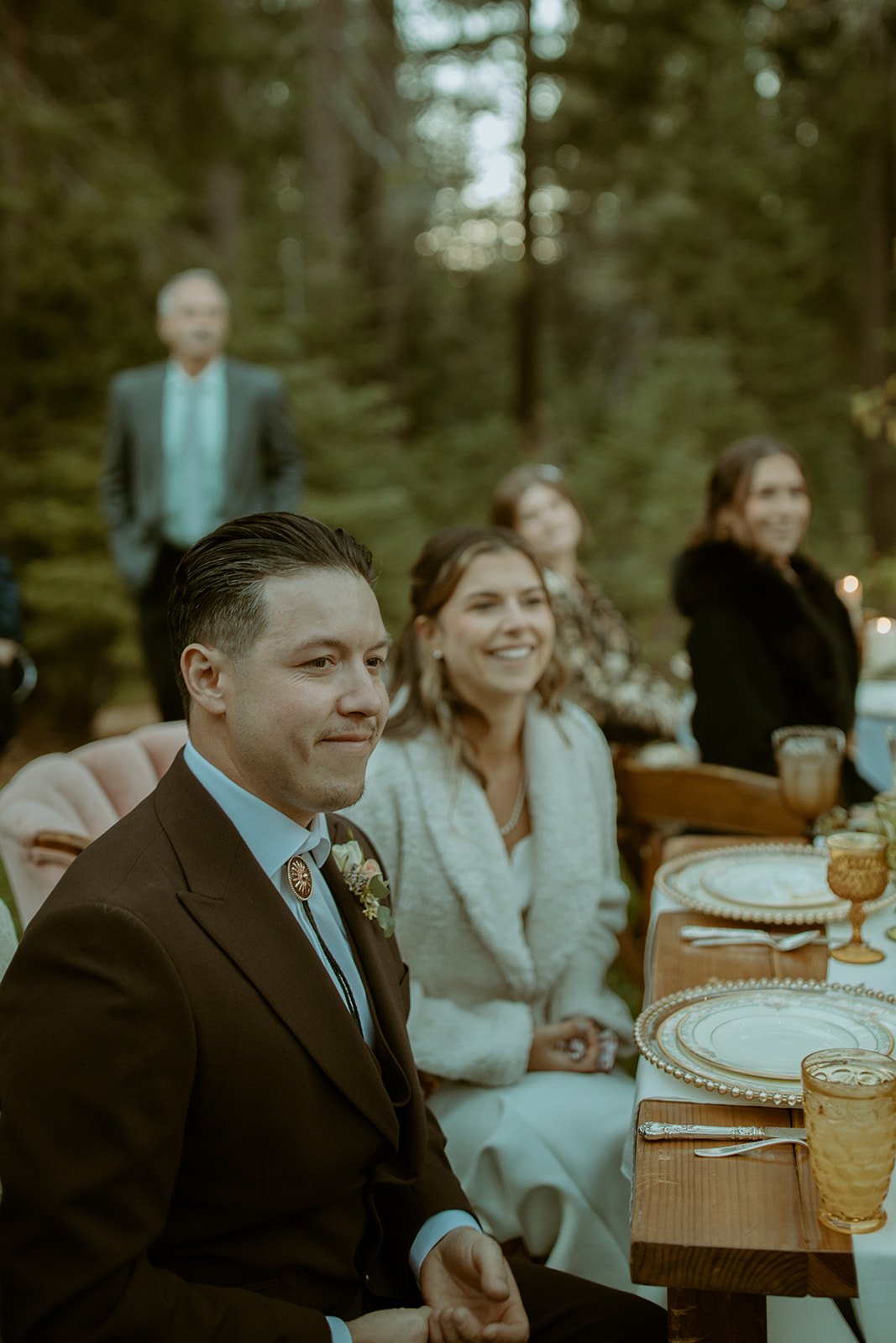 Emily and Devin smile at their table as a toast begins