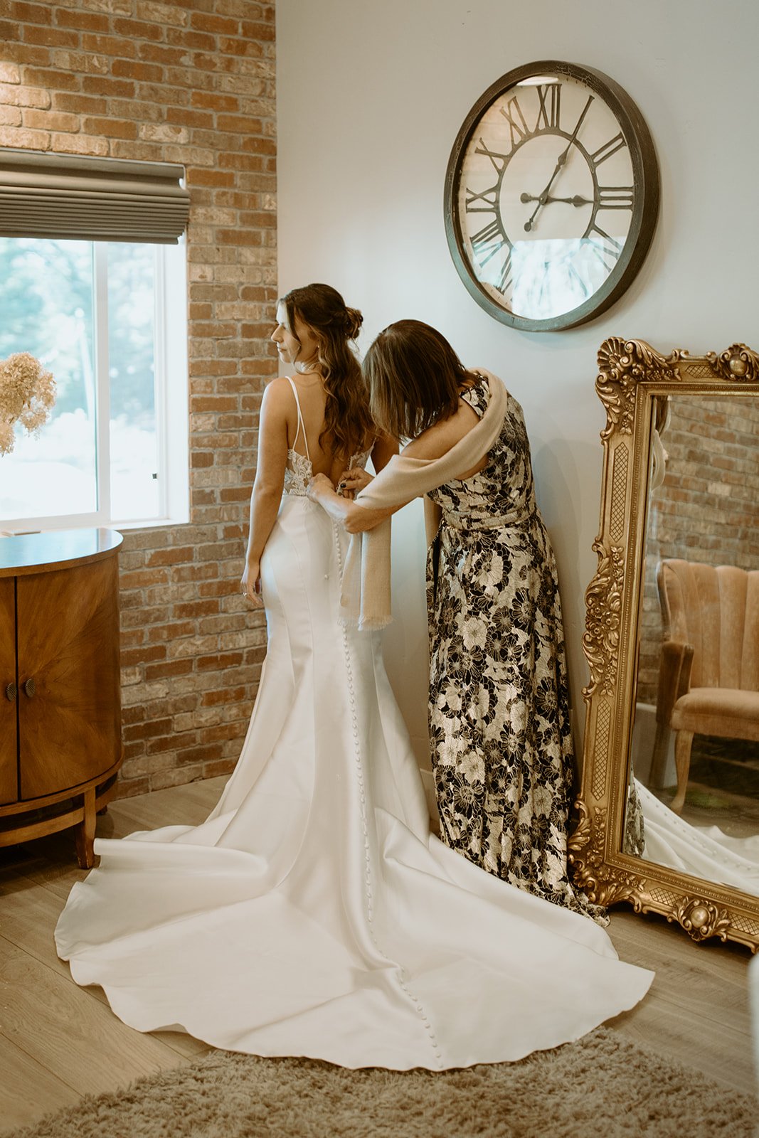 Emily's gown gets laced up by the gold mirror