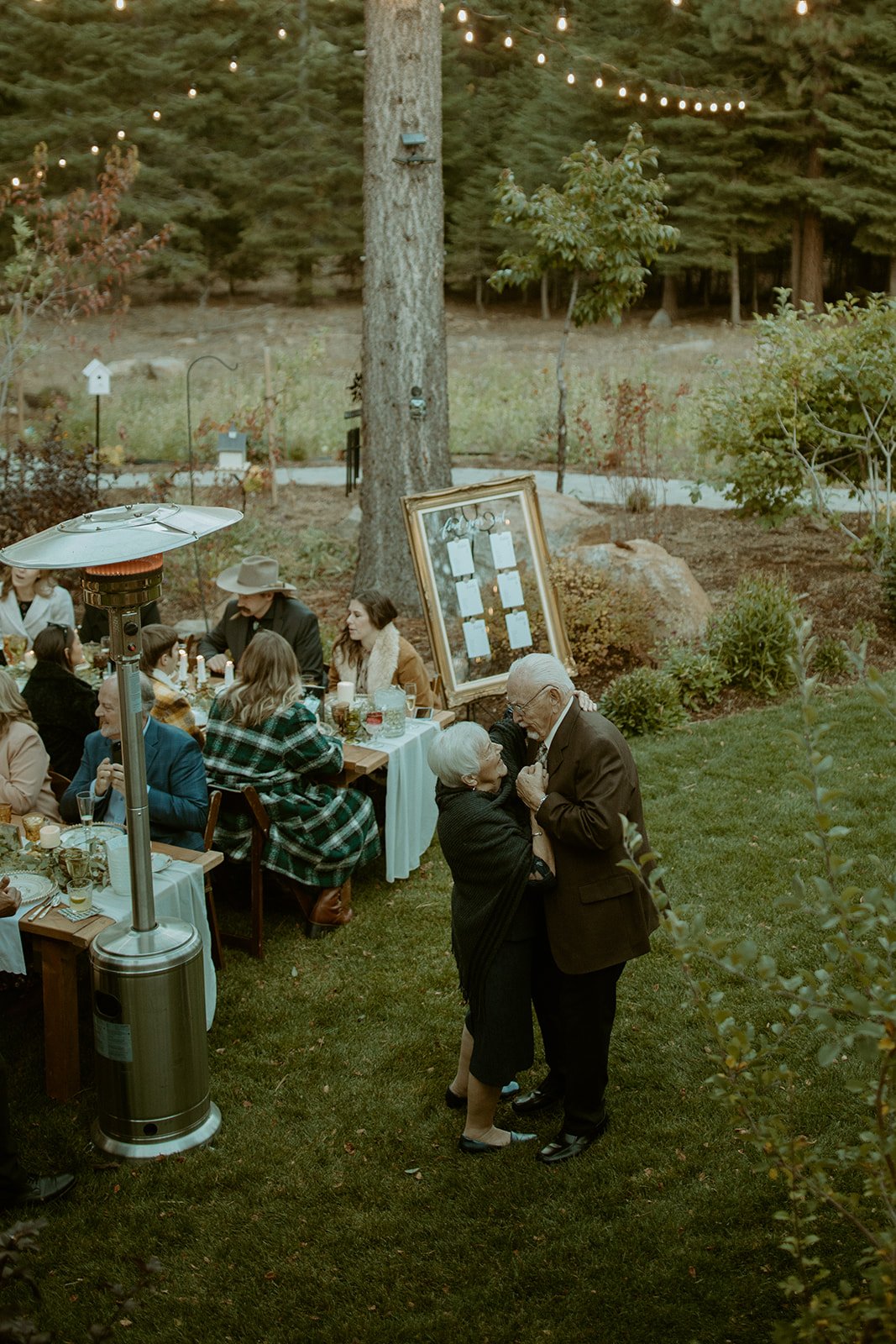 An older couple dances on the lawn beside the dinner tables