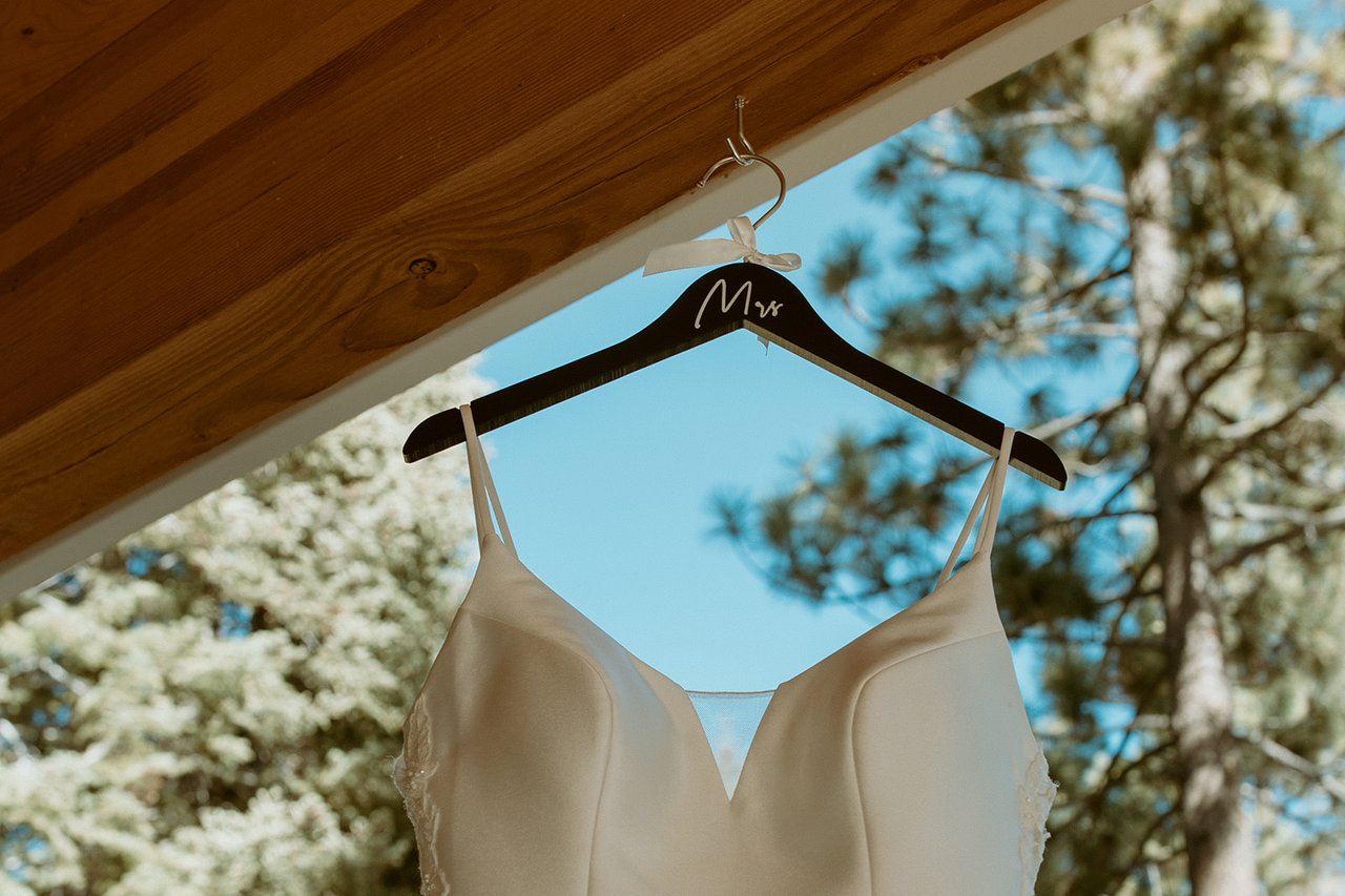 A wooden hanger with "Mrs" holding the gown under the porch roof