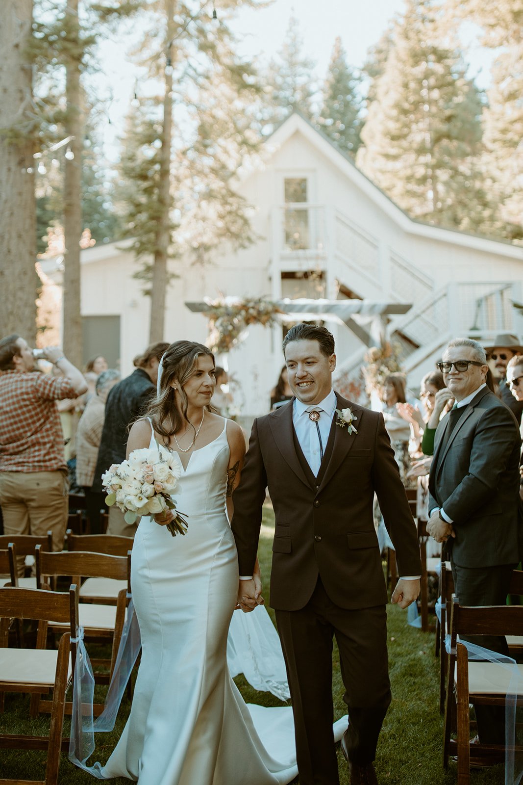 Emily and Devin walk back up the aisle hand in hand, smiling