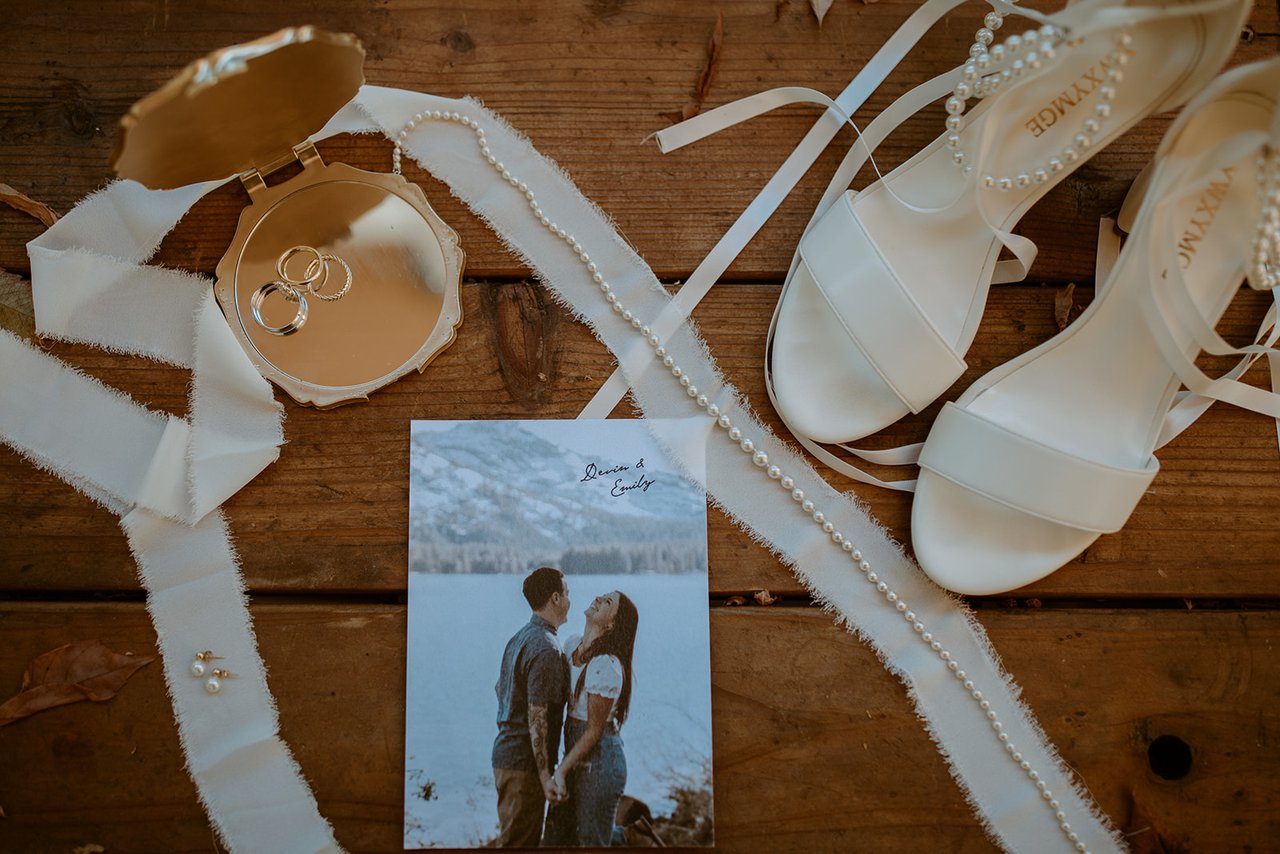 The rings, her heels, silk ribbon and the invitation on weathered wood