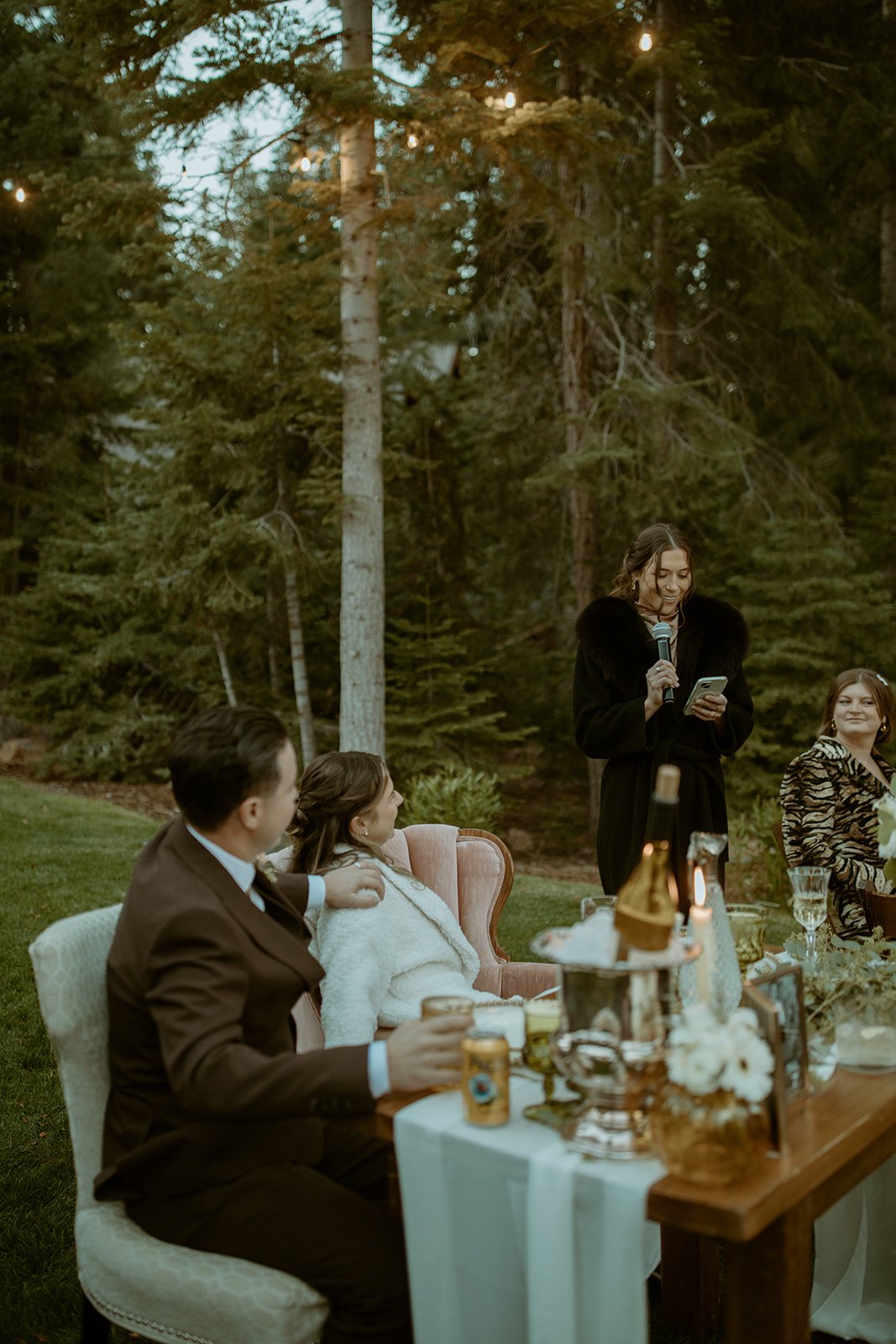 A friend gives a toast as Emily and Devin laugh at their table
