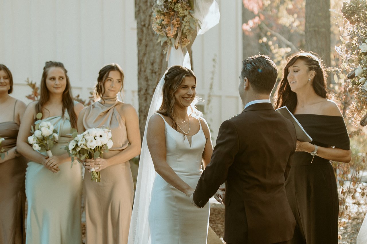 Emily laughs during the vows as her bridesmaids smile