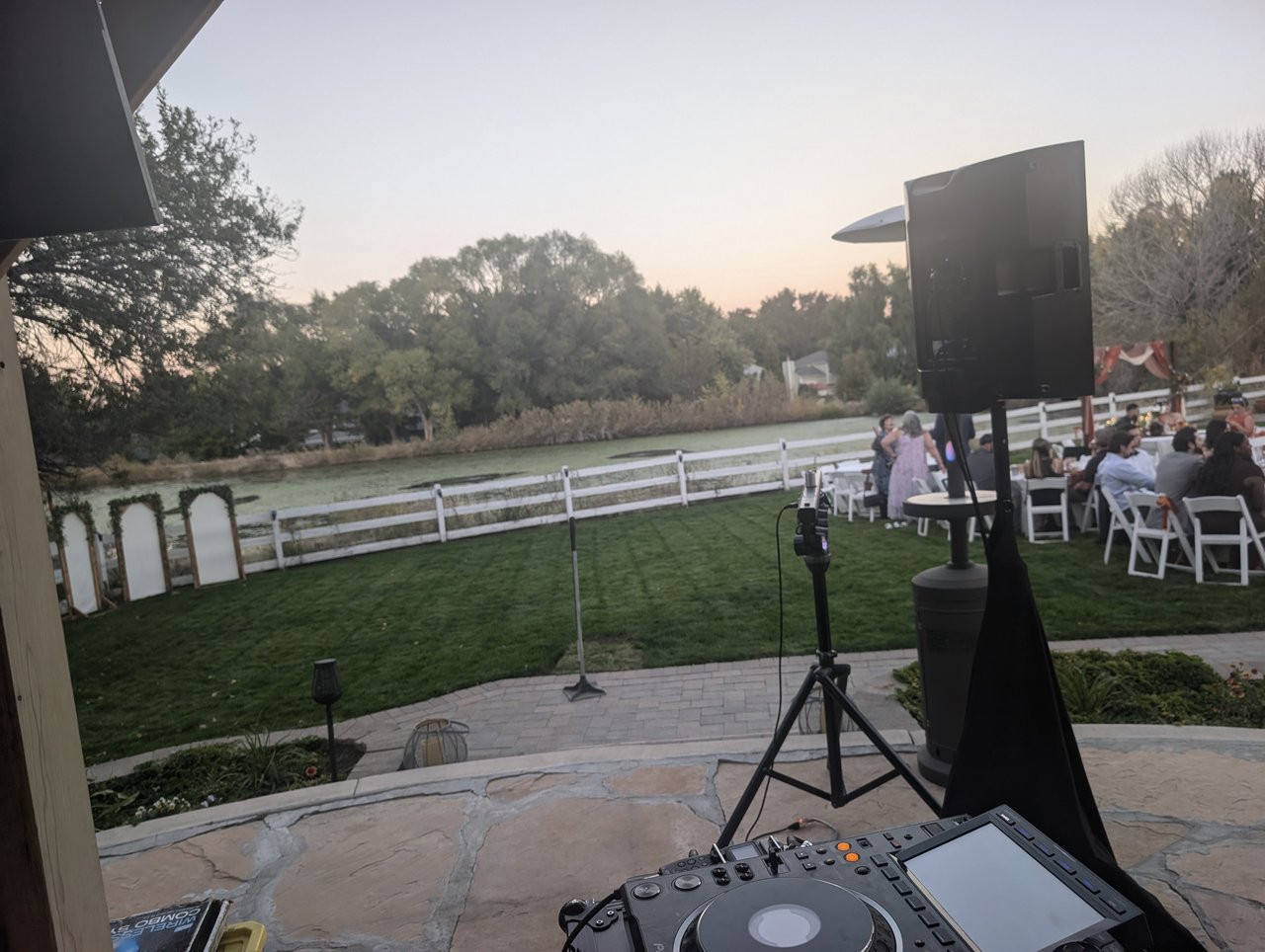 The view from the DJ booth at dusk over the lawn, the white fence and the water beyond