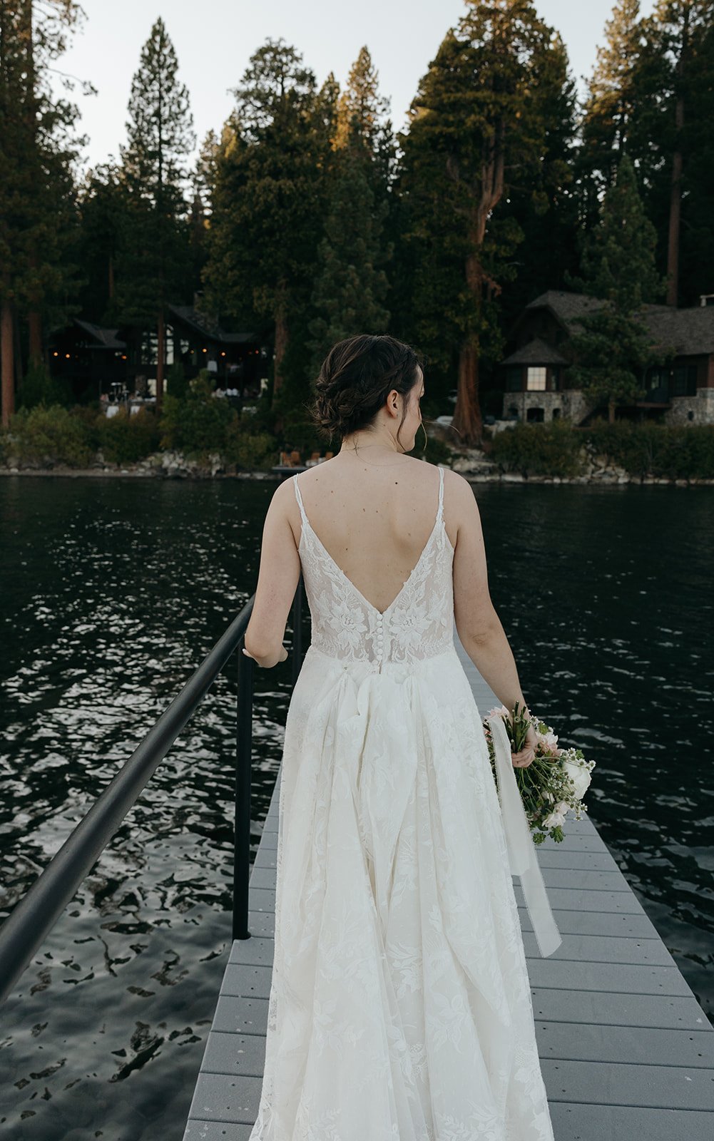 Emma walks out on the pier showing the open back of her lace dress