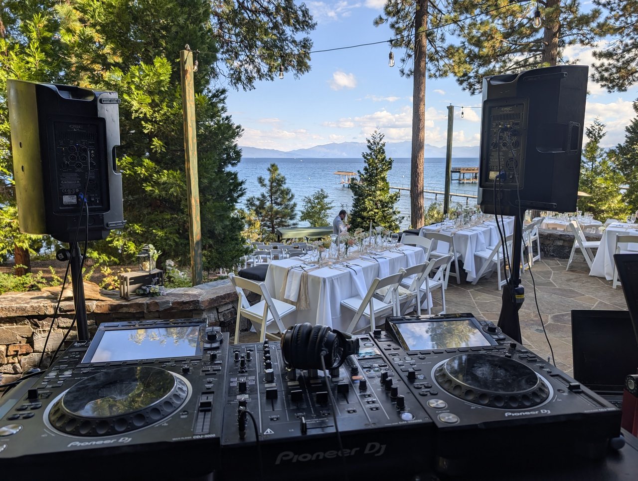 The DJ booth set up above the reception tables, Lake Tahoe and the mountains beyond the pines