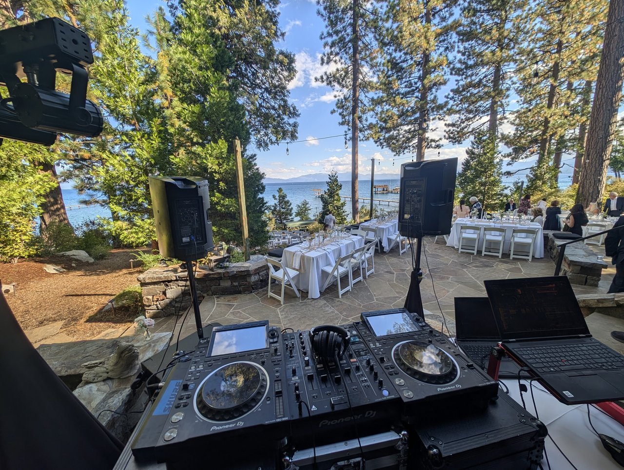 Pioneer DJ decks and speakers facing the long white reception tables on the stone terrace
