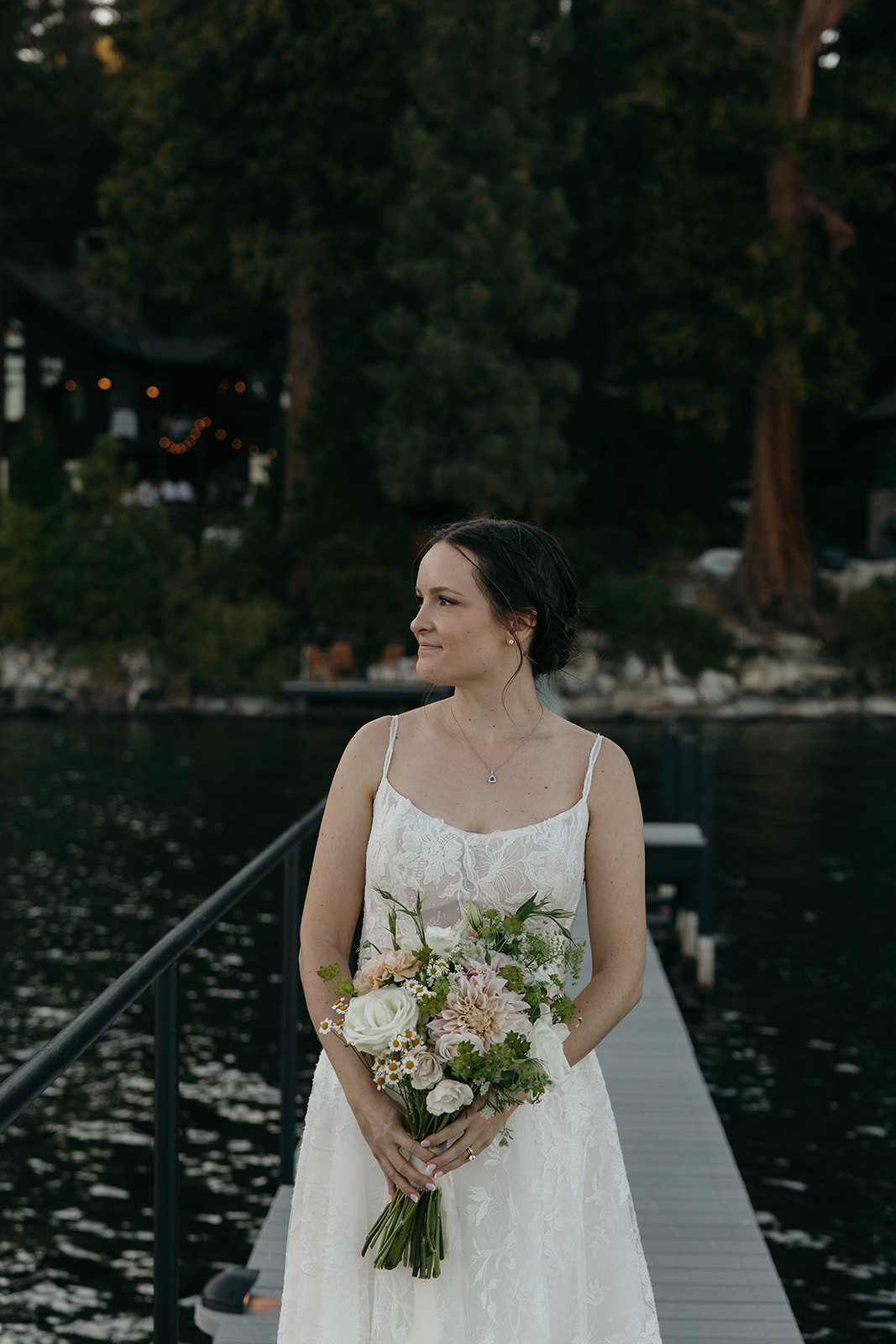 Emma looks out across the lake as she holds her bouquet on the pier