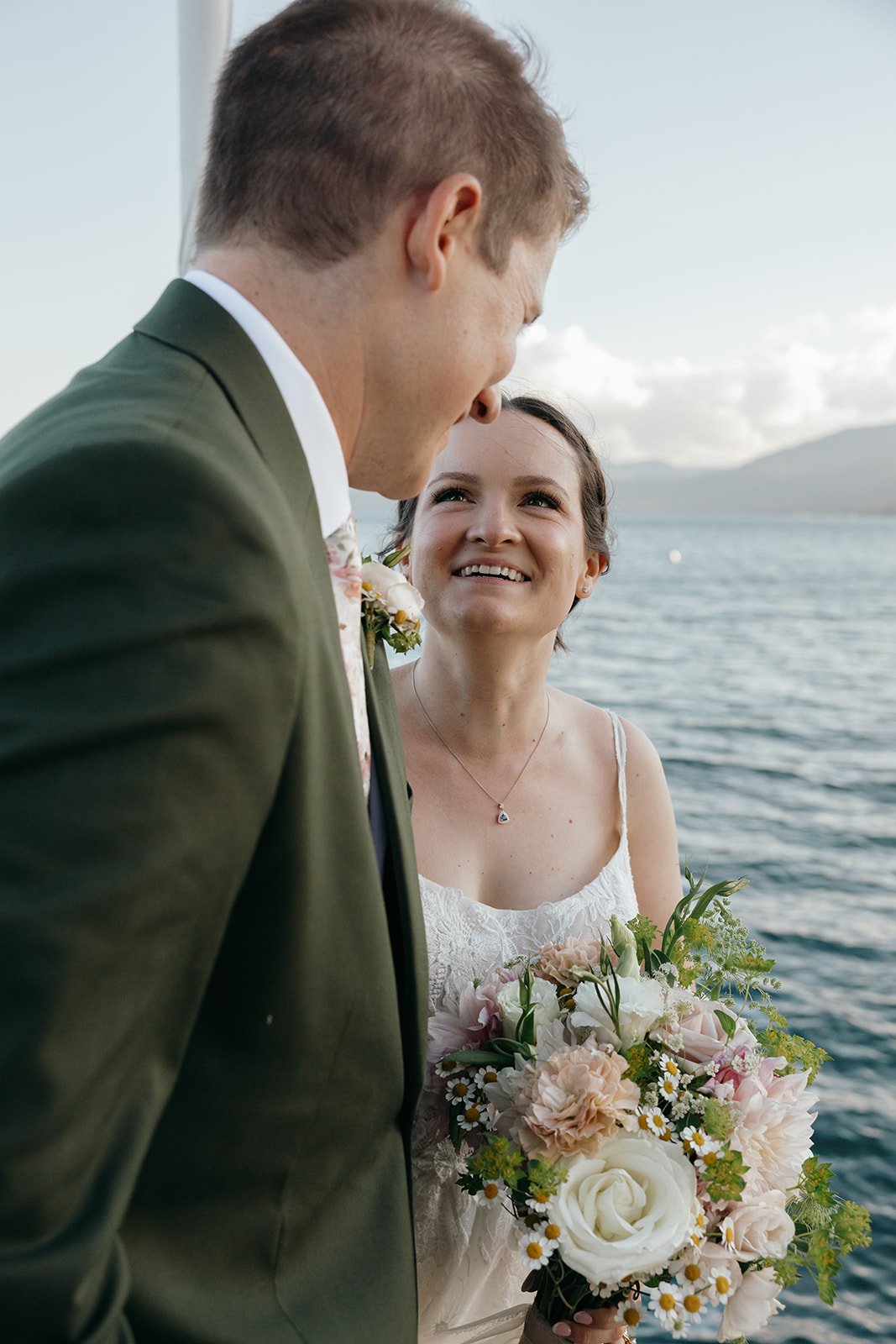 Emma smiles up at Jackson, her bouquet of roses and daisies held close
