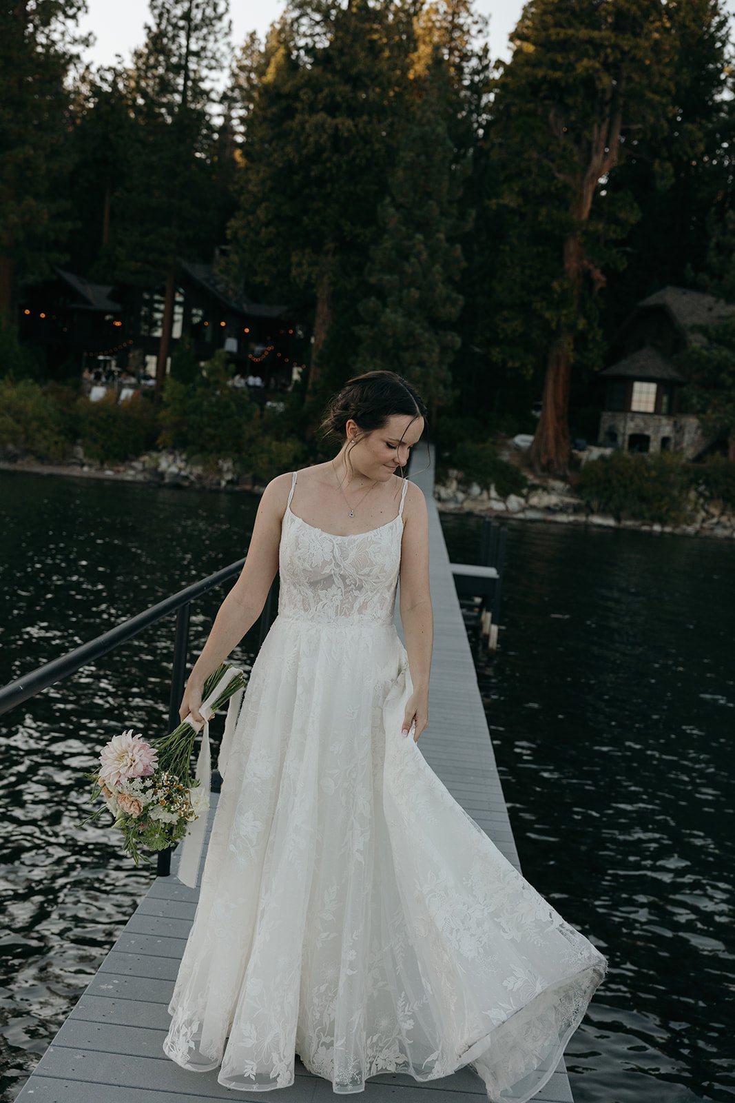 Emma walks along the pier holding her dress and bouquet