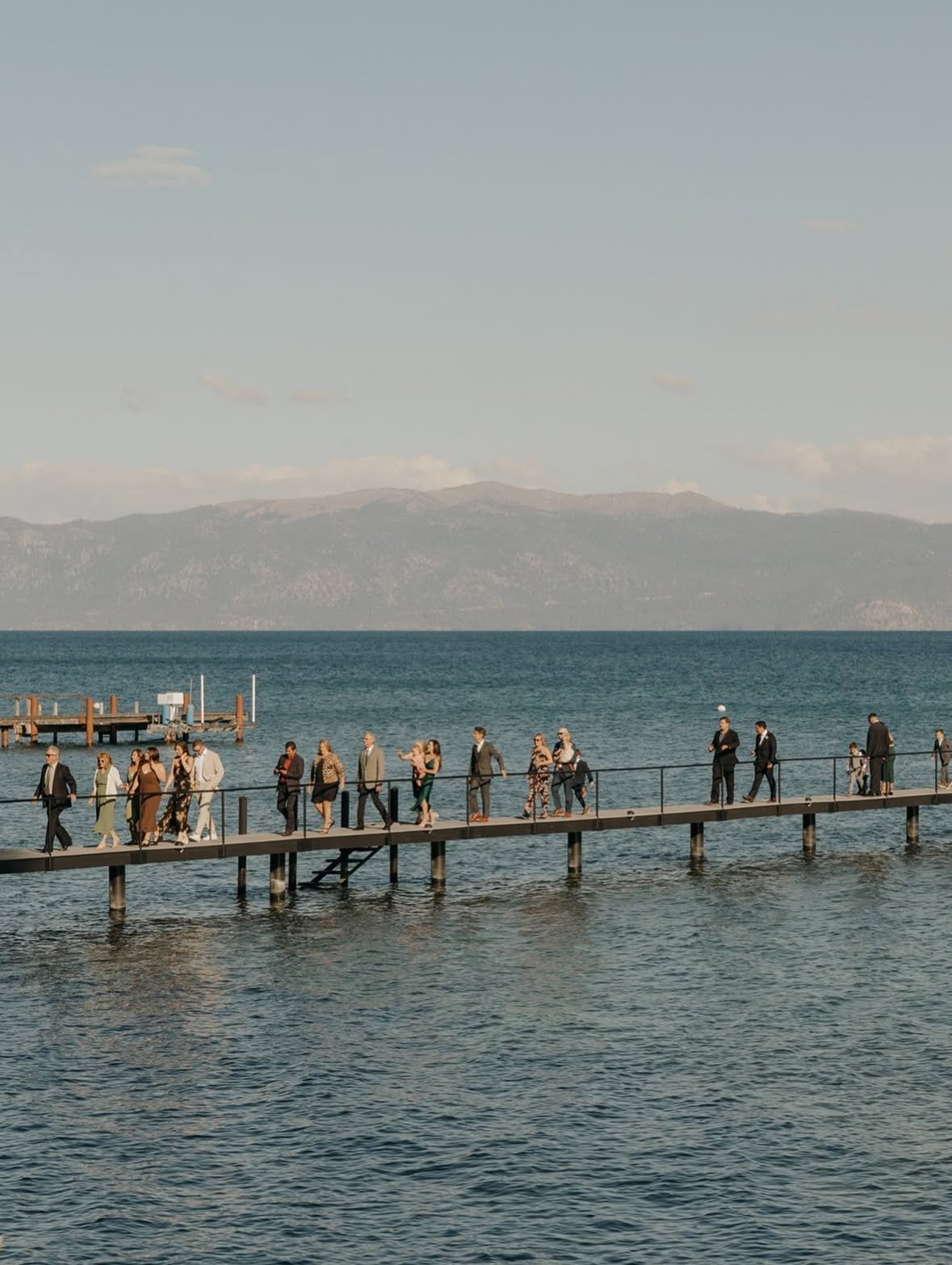 Guests walk out along the long pier over Lake Tahoe with the mountains across the water