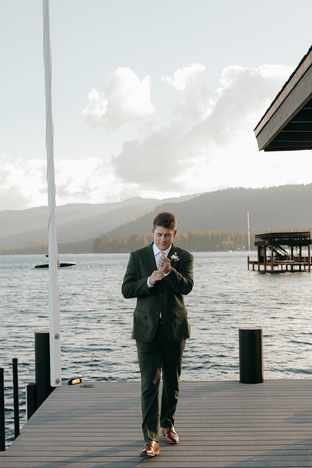 Jackson waits on the pier with the lake and mountains behind him
