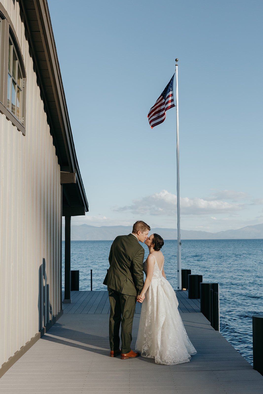 Emma and Jackson kiss at the end of the pier beside the boathouse and the flag