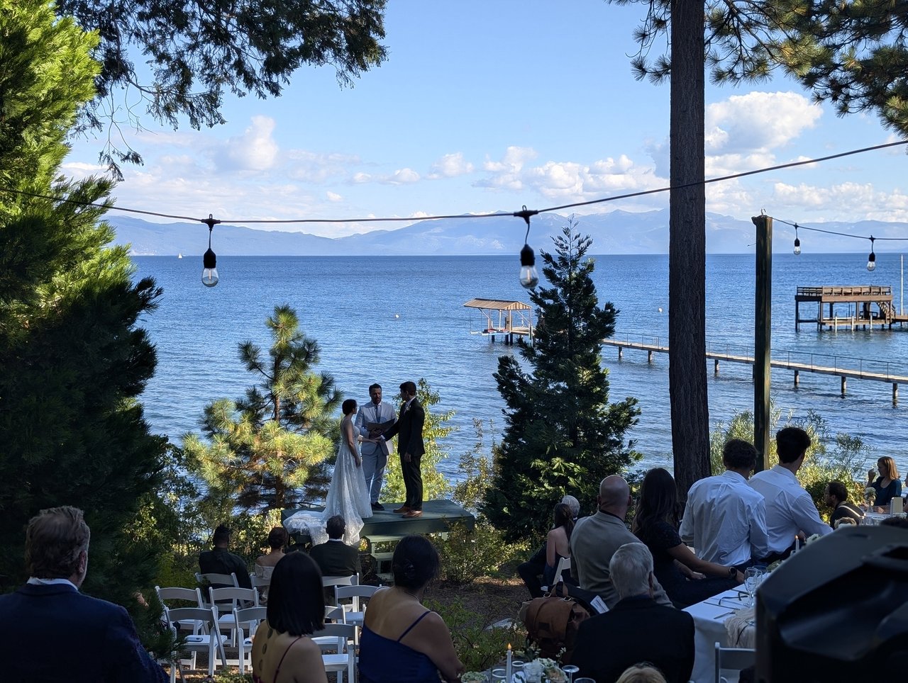 Emma and Jackson say their vows on a small stage at the edge of Lake Tahoe, guests seated under the pines and string lights