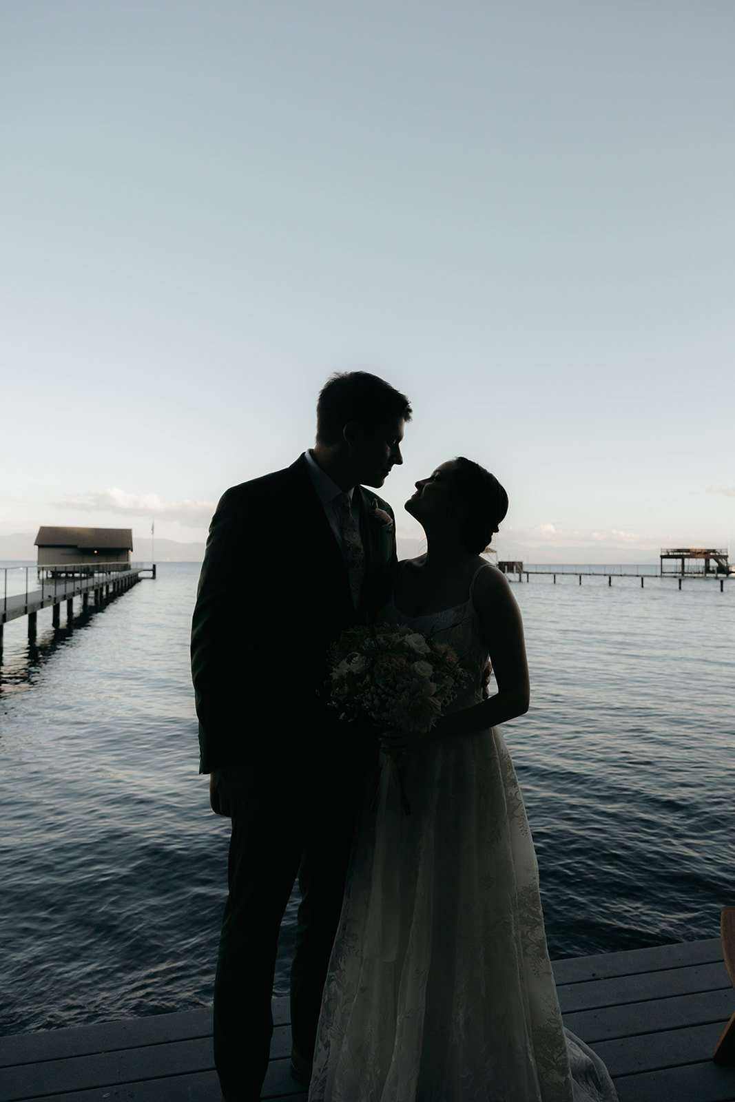 Emma and Jackson in silhouette on the pier at dusk with the lake behind them