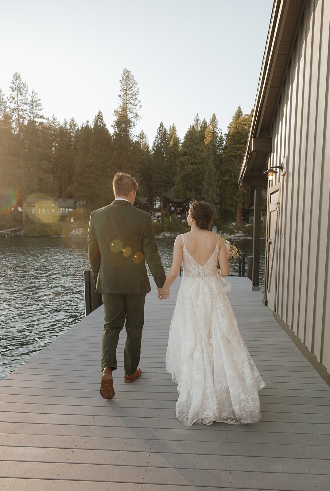 Emma and Jackson walk away hand in hand along the boathouse in the evening sun