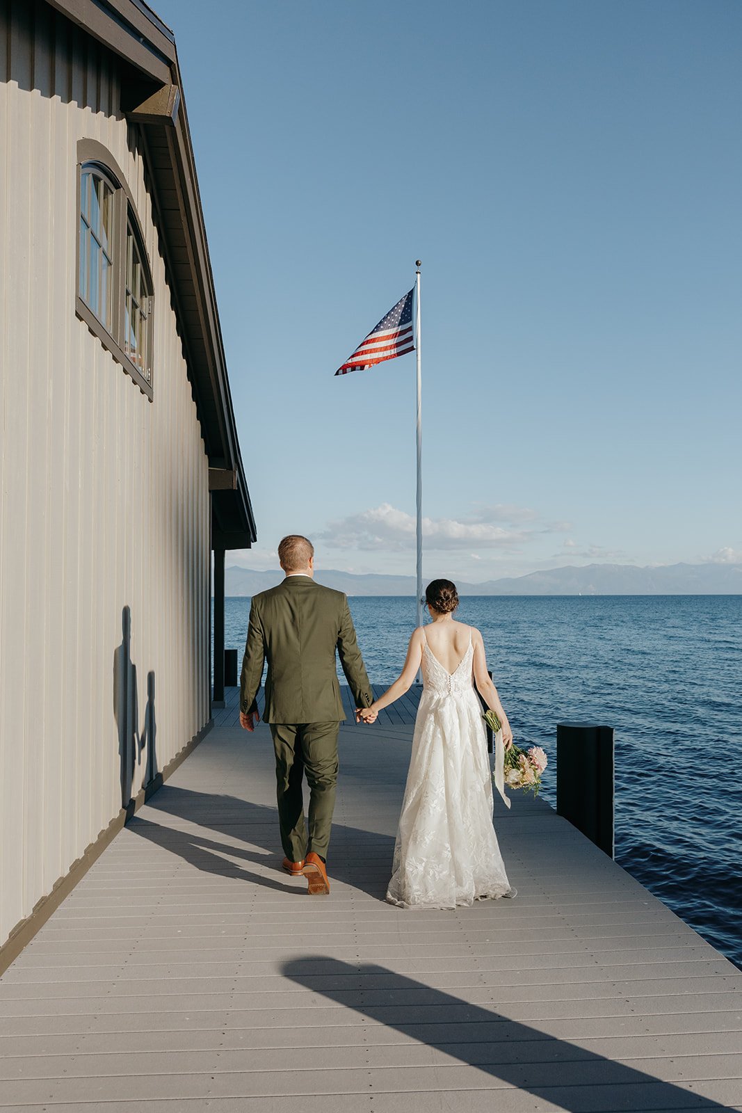 Emma and Jackson walk along the boathouse toward the flag at the end of the pier