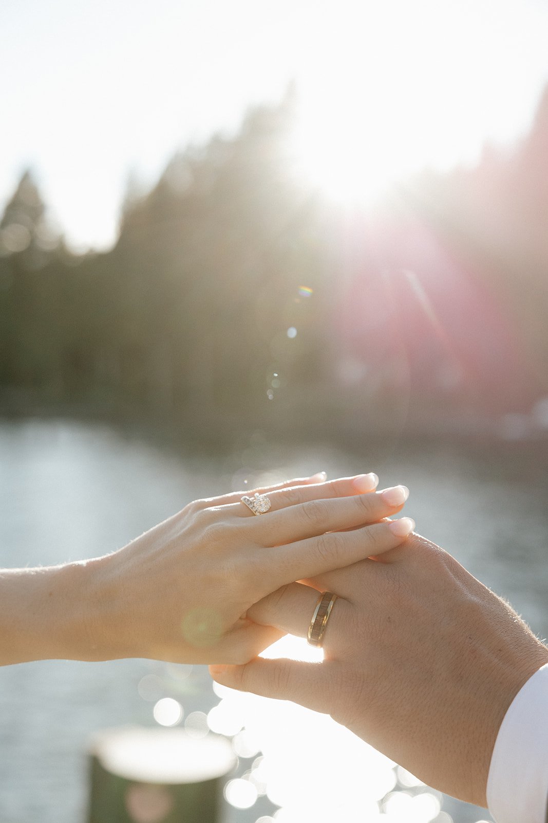 Emma and Jackson's hands and wedding rings against the bright lake light