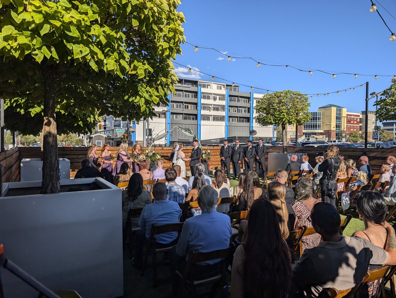 Hailey and Zen's ceremony on the bocce lawn at Renaissance Reno under string lights and a blue sky