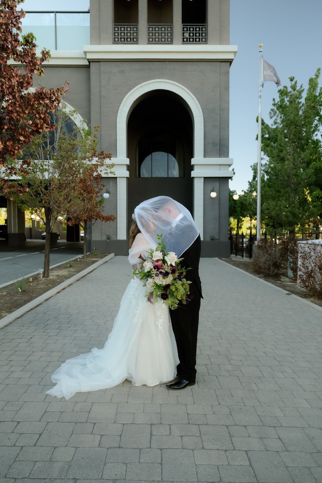 Hailey and Zen under her veil beneath the tall arch