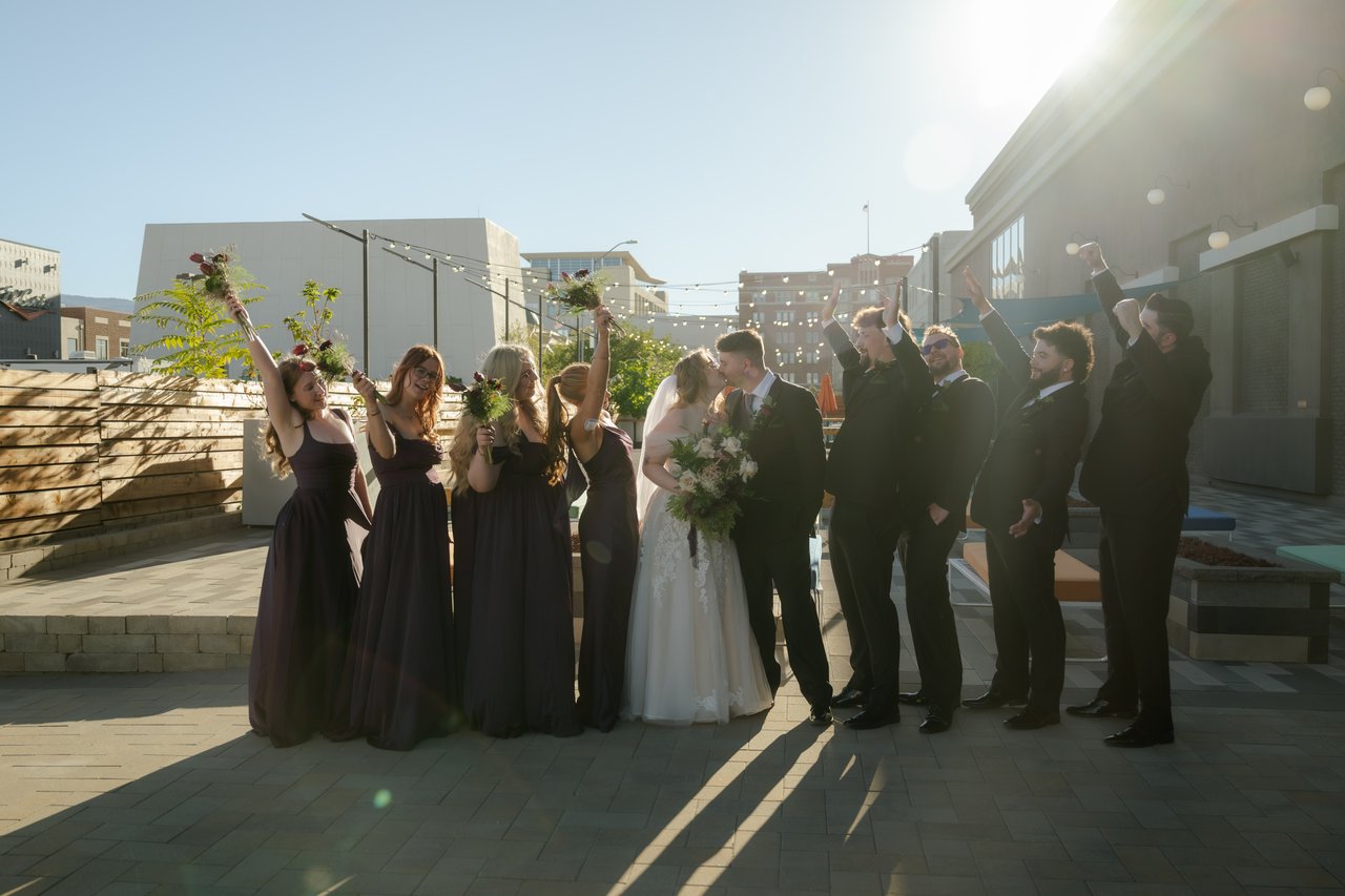 The wedding party cheers with bouquets in the air