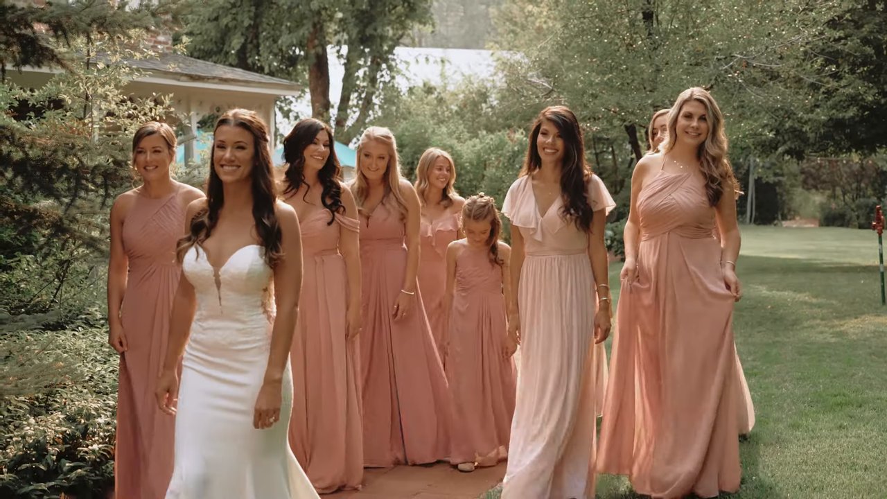 Jen walks across the lawn with her bridesmaids in blush dresses