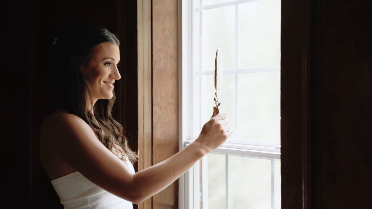 Jen smiles by the window as she gets ready