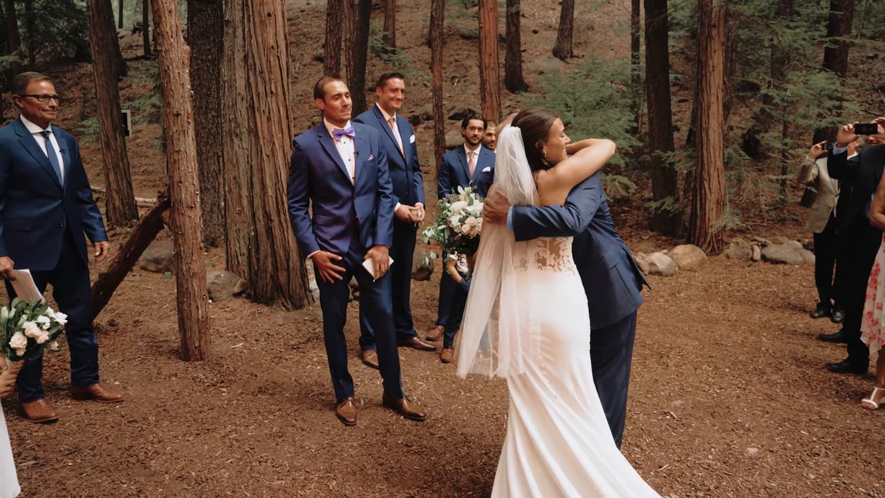 Jen hugs her dad at the end of the aisle as the groomsmen look on