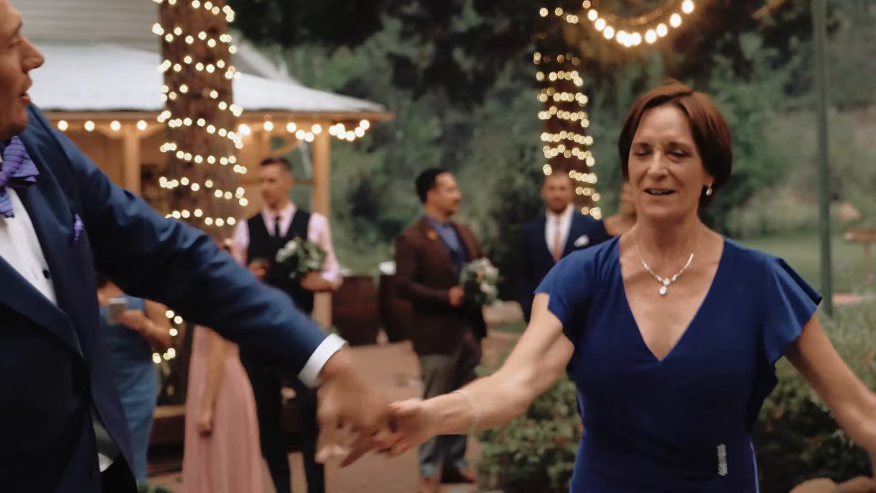 A woman in a blue dress smiles as she takes a hand for a dance