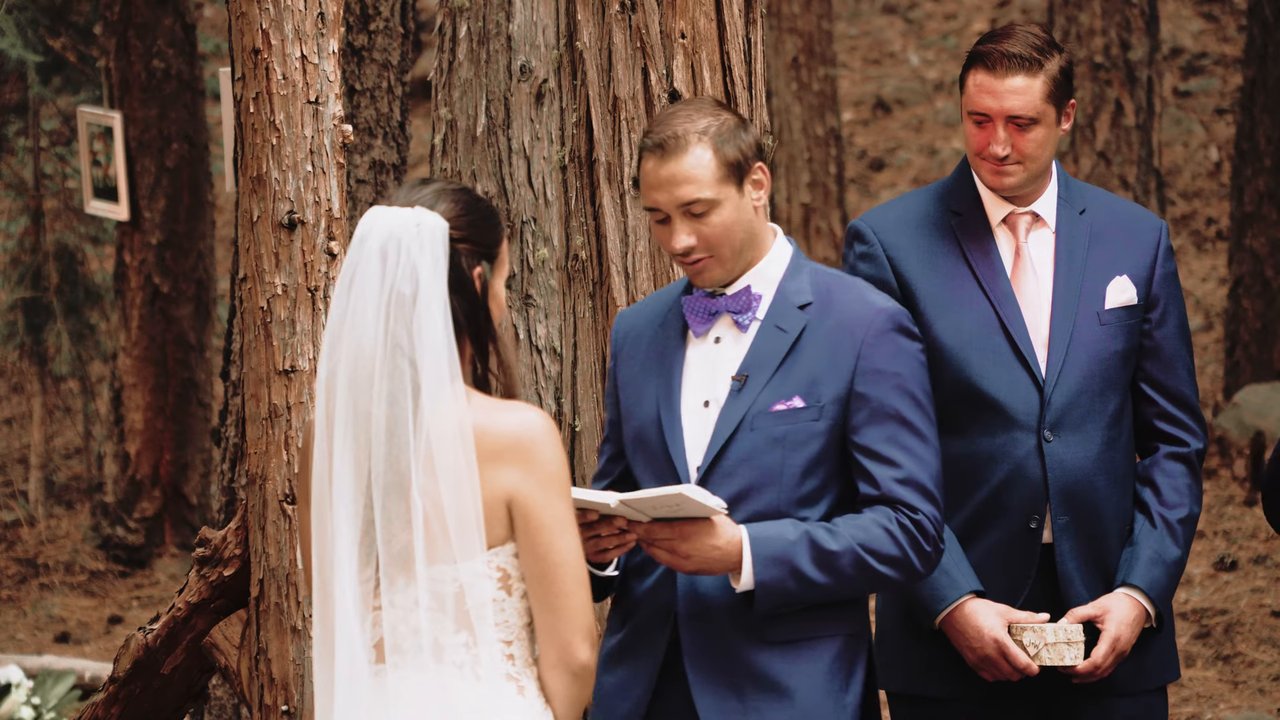 Wes reads his vows to Jen beneath the tall pines