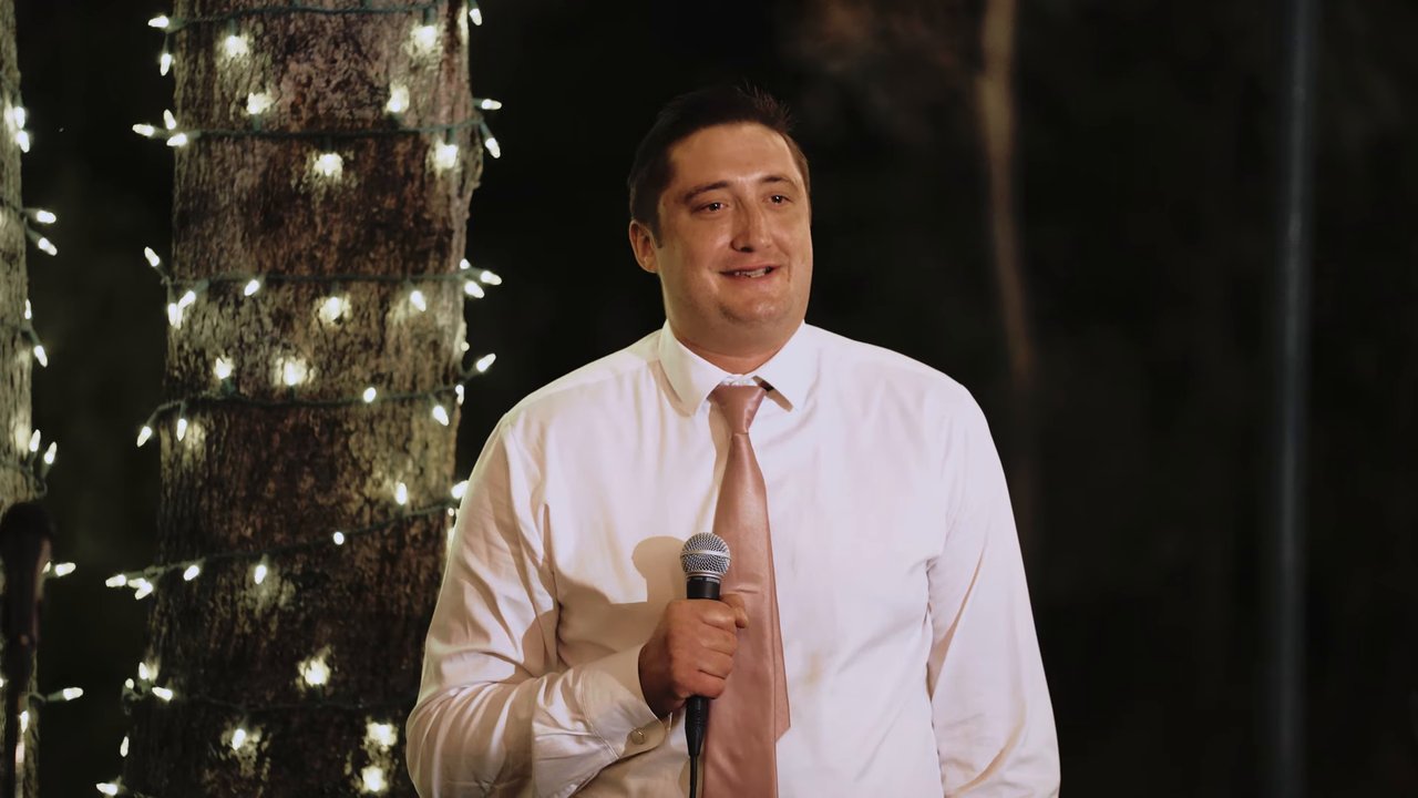 A groomsman smiles as he gives his toast