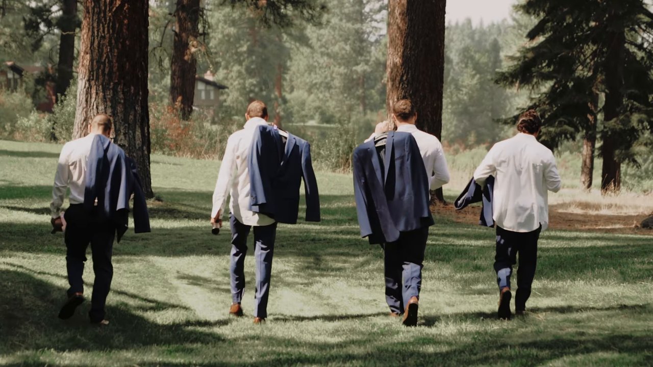 Wes and his groomsmen carry their jackets across the lawn