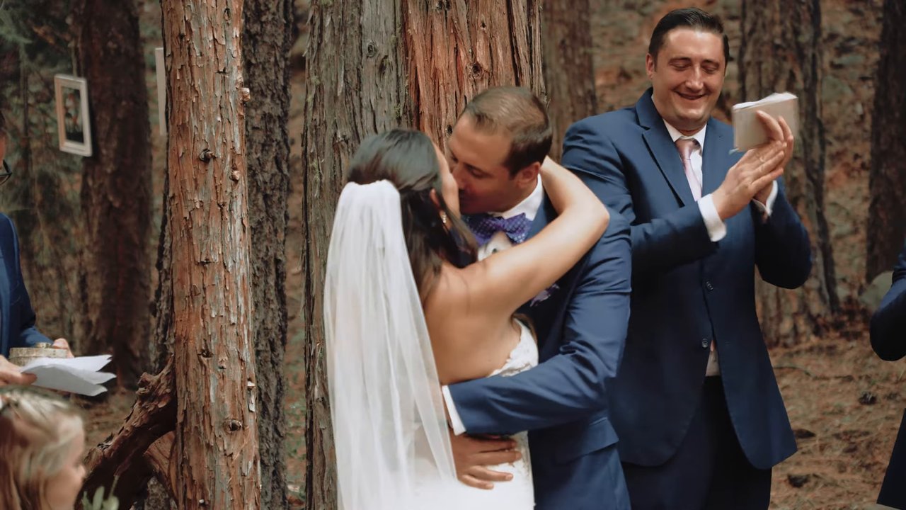 Jen and Wes embrace as a groomsman cheers beside them