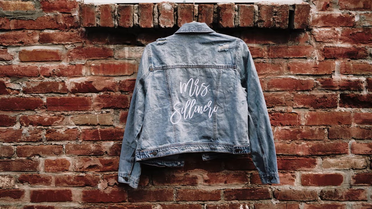 Jen's denim jacket with Mrs written across the back hangs on a brick wall