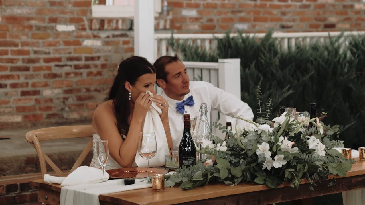 Jen and Wes wipe happy tears at their sweetheart table during the toasts