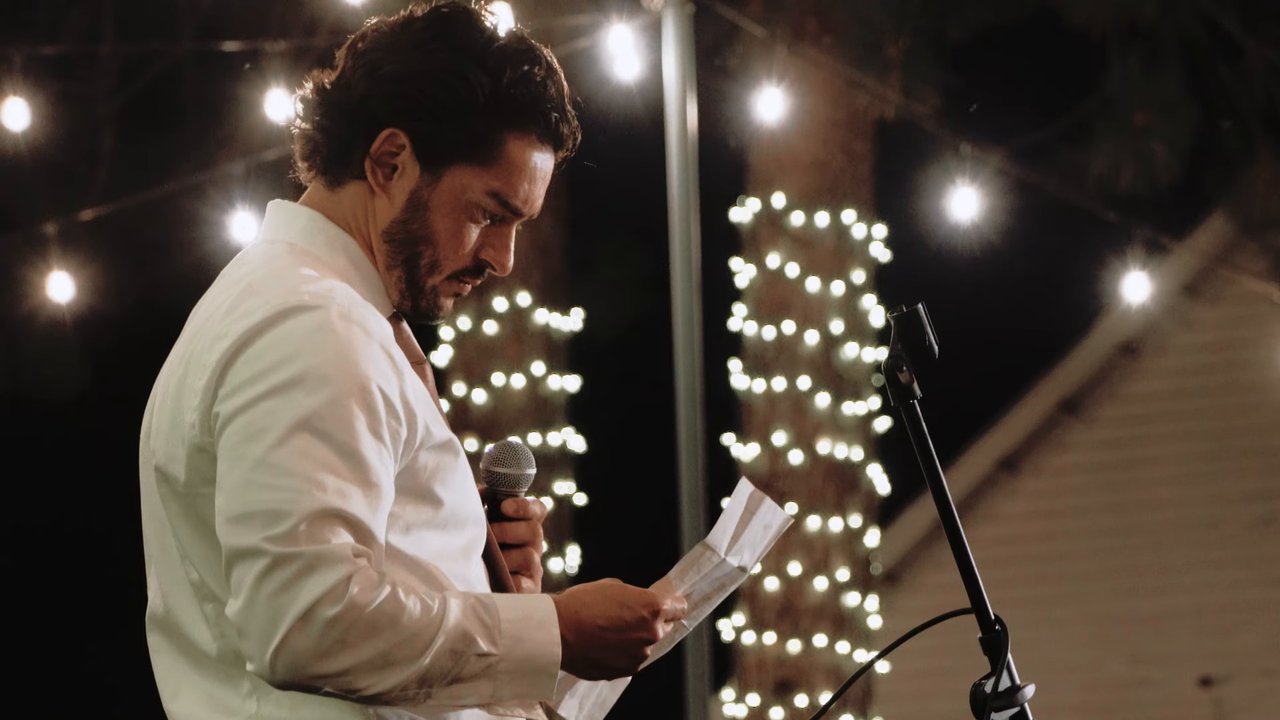 A friend reads his toast under the string lights