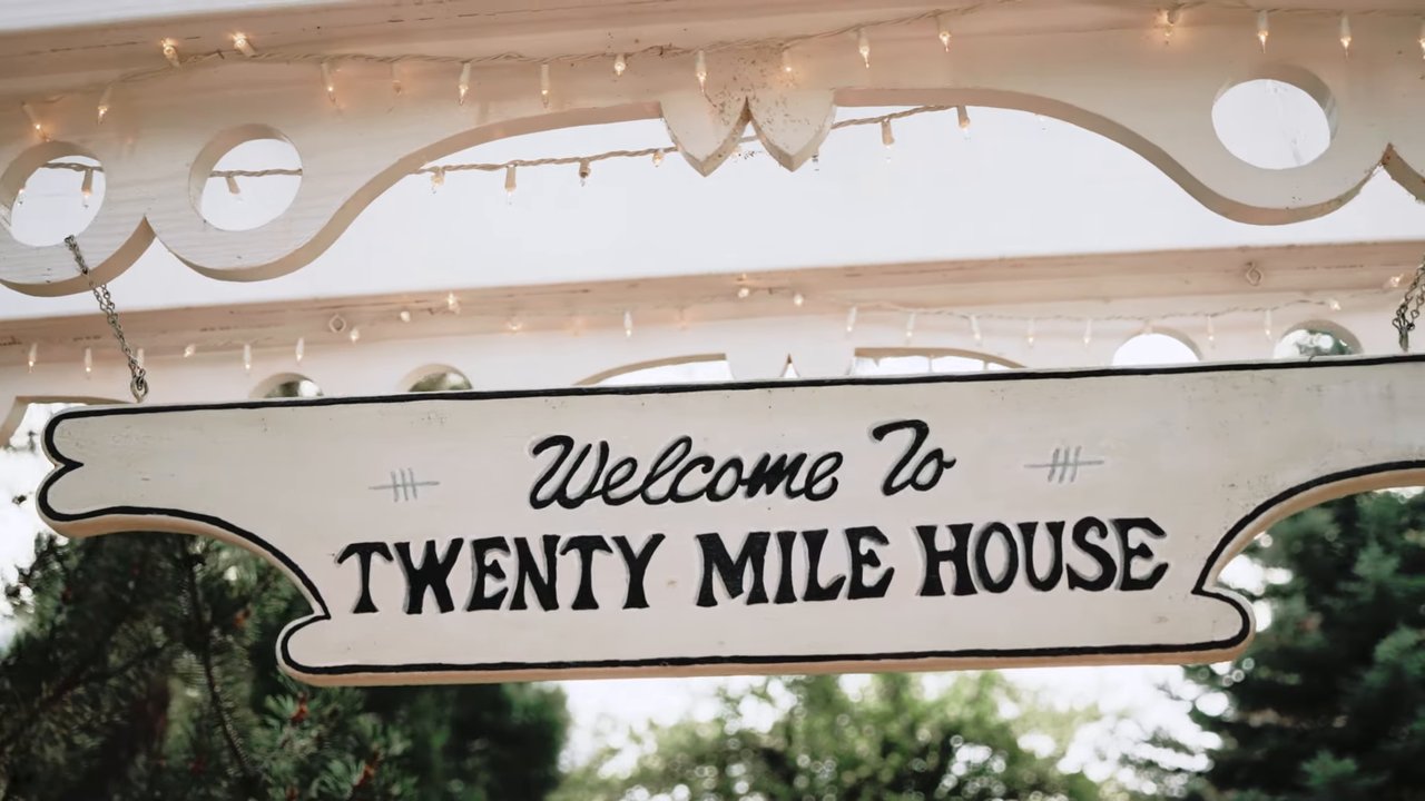 The Welcome To Twenty Mile House sign under the porch trim
