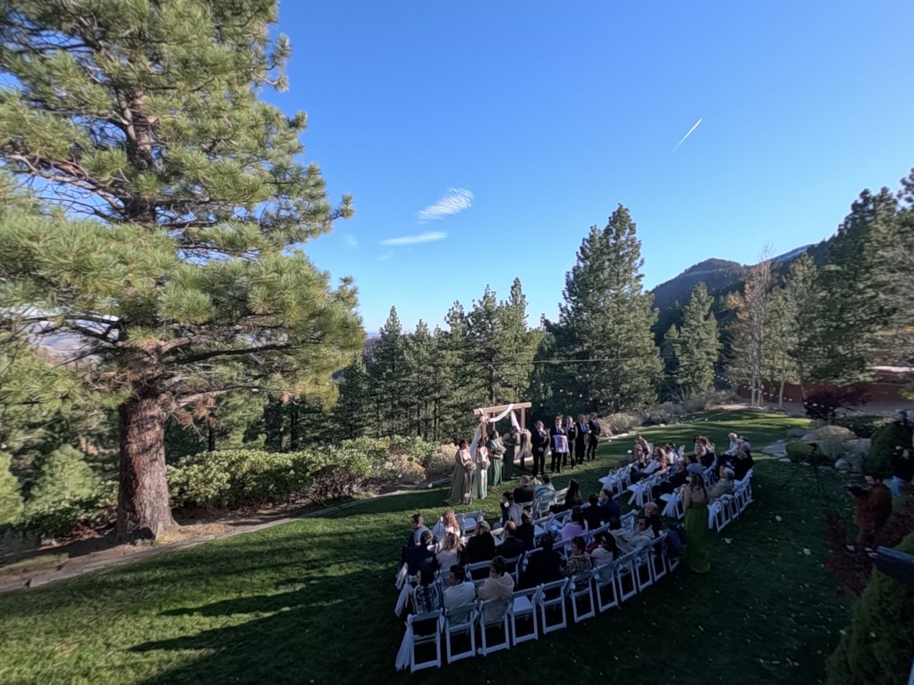 The unplugged ceremony on the lawn at Tannenbaum, under a tall pine with the mountains and blue sky behind
