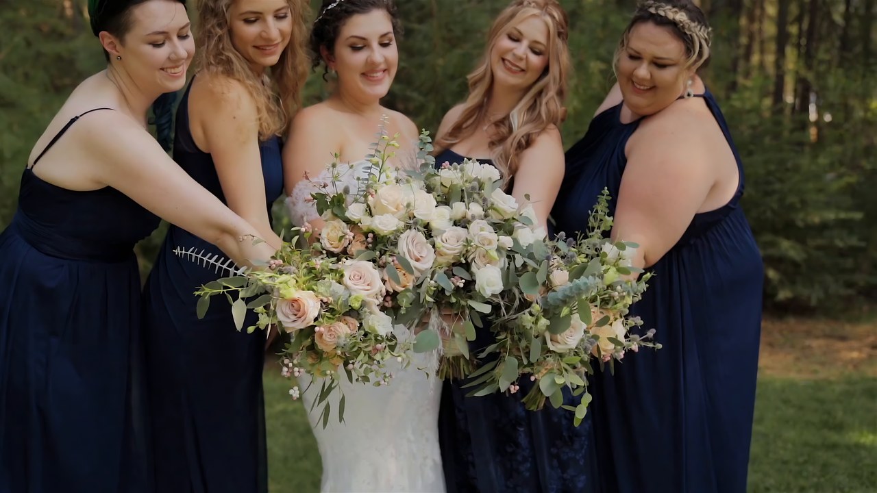 The bridesmaids hold their bouquets in the pines before the ceremony