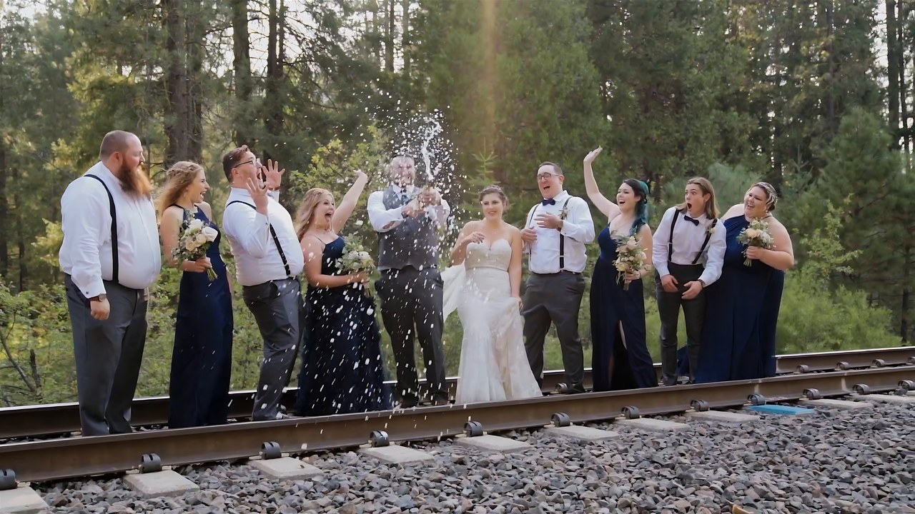 Champagne sprays over Jessie and Jeff on the railroad tracks